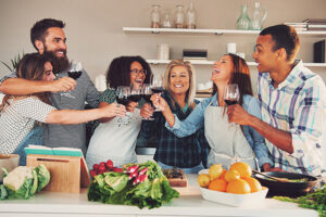 Fun group toasting wine glasses while cooking